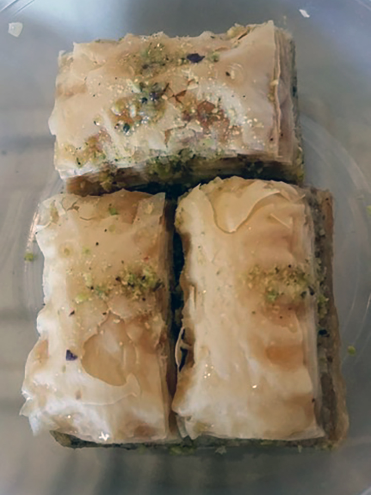 Three pieces of baklava with crumbled pistachio sprinkled on top.